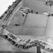Oblique aerial view centred on the cropmarks with the farmhouse, steading and plantation adjacent, taken from the SW