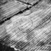 Oblique aerial view centred on the cropmarks of a circular settlement with outworks, taken from the N.