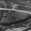 Skateraw, oblique aerial view, taken from the NNE, centred on the cropmarks of ring-ditches, a pit-circle and possible cists. An enclosure is visible in the top right-hand corner of the photograph, and reinforced flasks from the Torness Powerstation being loaded are shown in the top centre half.