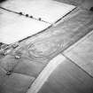 Oblique aerial view centred on the cropmarks of the fort, linear cropmarks and boundary ditches, taken from the NE.