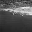 Oblique aerial view centred on the remains of the pile construction yard, scuttled ships, railway yard and railway, taken from the WSW.