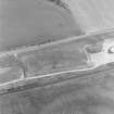 Oblique aerial photograph of Drumflower taken from the SW, centred on the cropmarks of barrows, pits and a pit-alignment with the line of a military road to the N.