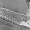 Oblique aerial photograph of Drumflower taken from the S, centred on the cropmarks of barrows, pits and a pit-alignment with the line of a military road to the N.