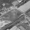 Oblique aerial photograph of Parkneuk taken from the SW, centred on the cropmarks of barrows and pits, with possible quarry pits of a Roman road and the line of a military road to the upper left of the photograph.