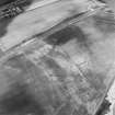 Oblique aerial view centred on the cropmarks of the pit-circle, pit-setting, possible enclosures, field boundary, linear cropmarks and pits, taken from the SE.