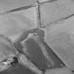 Oblique aerial view centred on the cropmarks of the enclosure and pits, taken from the NW.