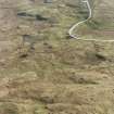 Oblique aerial view centred on the remains of the field-system and small cairns with hut-circle and small cairns adjacent, taken from the NW.