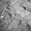 Oblique aerial view centred on the remains of the possible enclosure, hut-circle and small cairns, taken from the ESE.