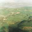 General oblique aerial view looking over the field-system, abbey and village towards the Solway Firth, taken from the WNW.