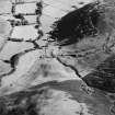 Oblique aerial view of Fiddleton centred on the remains of two scooped settlements, cultivation terraces and a cottage, taken from the NW.