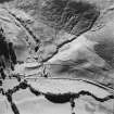 Oblique aerial view of Fiddleton centred on the remains of two scooped settlements, cultivation terraces and a cottage, taken from the E.