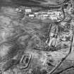 Oblique aerial view centred on the reservoir dam with quarrying associated with its construction, farmstead and enclosures adjacent, taken during low water from the SSW.