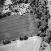 Pitmuies, oblique aerial view, taken from the W, centred on the cropmarks of a pit-circle and a possible unenclosed settlement, linear cropmarks and rig. Pitmuies country house and garden are visible in the top left-hand corner of the photograph.