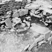 Excavation photograph : hearth with low kerb flanked by circular flat slab.