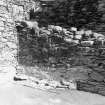 Excavation photograph : NE corner of E range showing E wall of building overlying remains of earlier wall (f211), from SW.