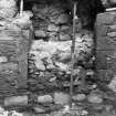 Excavation photograph : doorway on S side of N range, its rubble blocking partly removed and the overhanging masonry supported by an acro prop, from north.