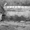 Excavation photograph : fireplace in N wall after removal of hearth 208 showing underlying sand f213 and rubble foundations in front of hearth, from N.