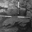 Excavation photograph XXII corn-roasting floor stone with wall section behind charcoal pit below