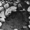 Excavation photograph - V view looking down into charcoal pit below corn roasting floor in circular structure showing low walling on western segment and broken floor slab.