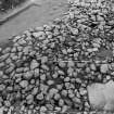 Excavation photograph : cairn from above - cleaned to structural level, and cist slab, north-east sector.