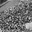 Excavation photograph : cairn from above - cleaned to structural level, and cist slab, north-east sector.