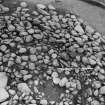 Excavation photograph : cairn from above - cleaned to structure level, and cist slab, in north-east sector.