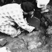 Excavation photograph : area X/H - removal of quernstone 1418.