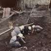 Excavation photograph : area M - uncovering skeleton in coalyard.