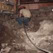 Excavation photograph : contractor's working removing dwarf wall beneath cart shed fireplace.