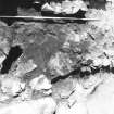 Excavation photograph - Detail of crucible (?) 46 beneath the flags of fireplace 34 from E