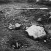 Braidwood: excavation photograph. 
Foreground - Posthole 10 (13) with packers, after filling stone removed. Stones in ditch with silt or burnt material beneath them. 
Behind to right, stones covering Posthole 10A (14) (outer end of porch).