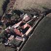 Oblique aerial view centred on the farmhouse, farmsteading, cart shed and cottages, taken from the SW.