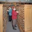 Interior.  View within library showing wooden cabinets containing drawers of index cards, cross-referencing Reports with reference books,journals and other records.  A large part of the library's holdings was sent to ICI Explosives headquarters in Australia in 1996, but the Index remained in Ardeer.  Also in the picture are Annette Kelly (right, Information Officer) and Sheila Conway (former Records and Reports Officer)