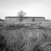 View from E of surviving Quinan stove or drying house, building R18, with concrete foundations of heater unit in foreground.  The 36 Quinan stoves were arranged symmetrically in pairs around a central heater unit or apparatus house.