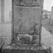 General view of East face of gravestone commemorating John Burry, 1744, in the churchyard of Little Dunkeld Parish Church, showing stone with portrait roundel, crossed bones, skull and hourglass.