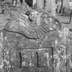 View of gravestone commemorating Daniel Thomson, 1721, in the churchyard of St Serf's Parish Church, Alva. with soul at the top of stone, 'Memento Mori' inscribed below and two carvings of the mason's castles in the panel.