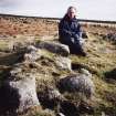 Mr Adam Welfare (RCAHMS) sitting on hut-circle wall