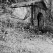 General view of exterior of well house, Bealach an Fhuarain, Inveraray Castle Estate, showing small stone building with pediment and vermiculated rustication over the arch entrance.