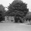 General view of St John's Cottage, Maybole, behind trees.