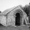 View of a burial vault W of the church, featuring a fine Romaneque doorway, once part of the old parish church from SE.