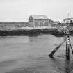 Distant view from W of boat house and slipway, with harbour wall in background