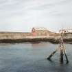 Distant view from W of boat house and slipway, with harbour wall in background