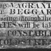 Detail of warning notice to vagrants and beggars adjacent to NE range's central block archway on NE side.