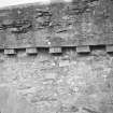 Detail of N elevation showing rubble construction, ashlar archway and brackets supporting parapet.