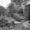 View from NE of NE gable of mill, with steps up to front door of mill house comprised of pieces of mill stone.