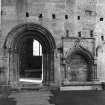 View from N of E processional doorway in cloister and wall arcade with bench adjacent.