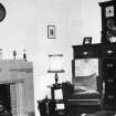 Interior.
View of living room showing chimneypiece, mirror, chair, chest of drawers and wall clock.