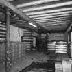 Alloa, Thistle Brewery, Basement floor, Cellar, interior
View from NW of storage area (NS 8881 9278)showing bottled beers awaiting dispatch. Bottling is not done on site. Note the ceiling where the beams are re-used (railway) rails, presumably for cheapness