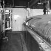 Alloa, Whins Road, Brewery, Brewhouse, mezzanine floor, interior
View showing heat exchanger (left), chilled liquor (water) tank right. First floor mill room area beyond. Here, the heat exchanger chills liquor (town water supply) to two degrees centigrade which is then used for heat transfer in the paraflow room (to cool the wort prior to entering fermentation). The recycled water is pumped into the chilled liquor vessel.