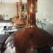 Alloa, Whins Road, Brewery, Brewhouse, first floor, interior
View from E showing the boiling copper (nearest the camera) and the two mash tuns beyond. The wort is pumped from the mash tun to the lauter tun (behind the camera) and then into the copper where hops and liquid sugar are added to make final ales or lagers. The copper has an external wort boiler or Collandria, which was added in 1994. This gives a more vigorous mash. The copper has an automatic level indicator in the form of a rod which rises as the copper fills up